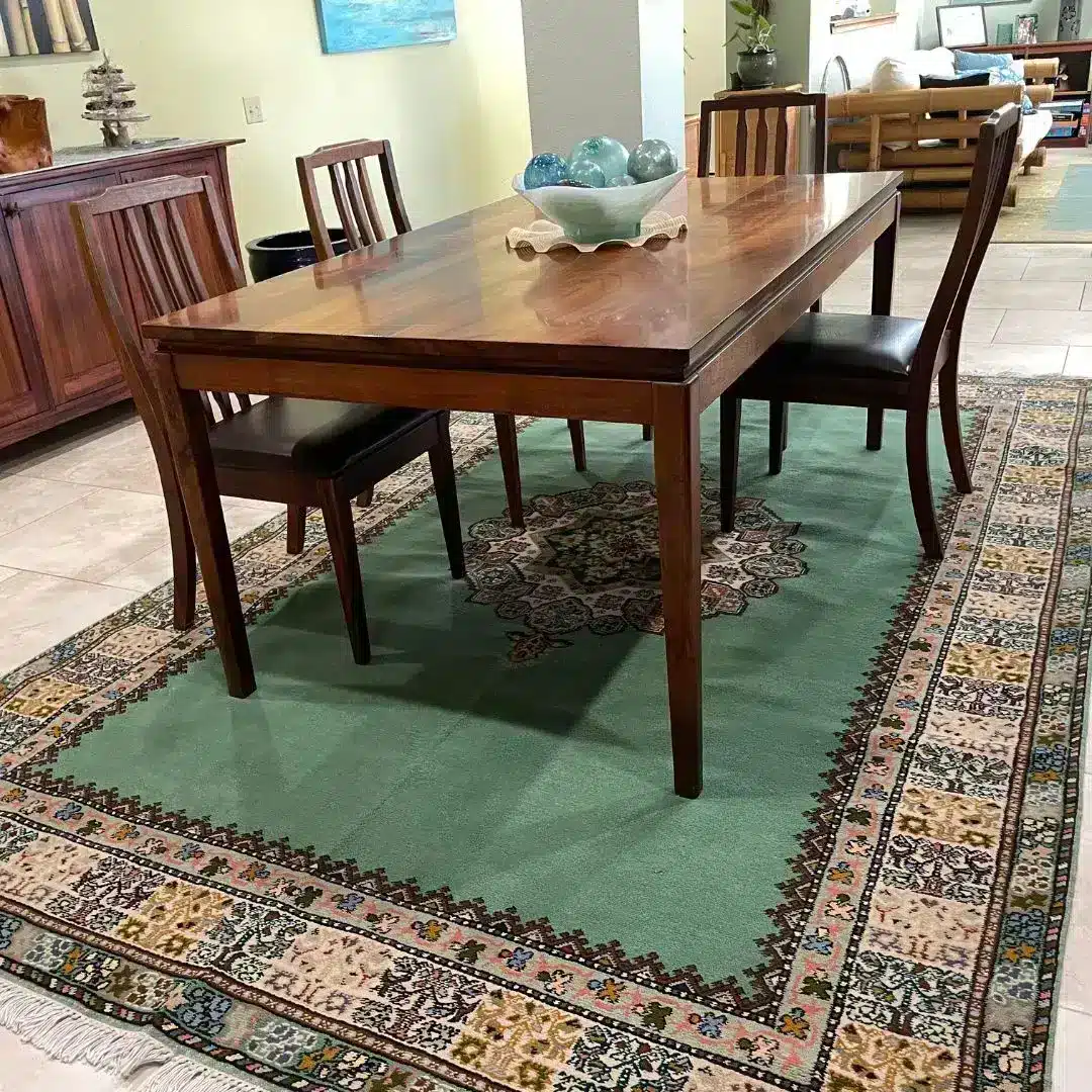 Sage green Persian-style rug with floral border under dark wood dining table and chairs