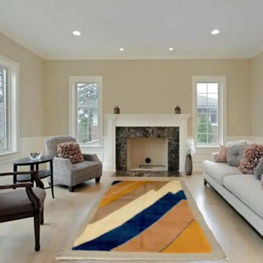 modern geometric washable area rug in neutral living room with sofa and fireplace